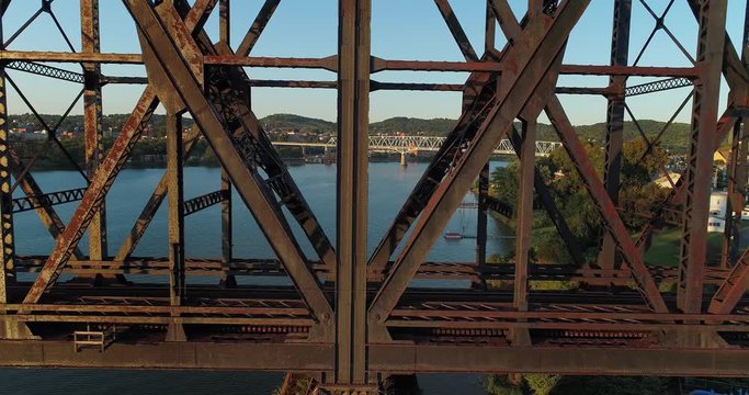 A dramatic profile aerial view of an empty, large railroad bridge spanning the Ohio River in Western Pennsylvania. The towns of Monaca and Rochester in the distance.  	