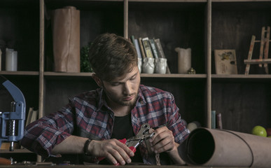 Young man leather manufacturer delicate working with tool hole punch