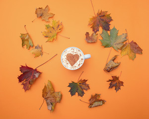 cappuccino with heart shape and autumn maple leaves around it