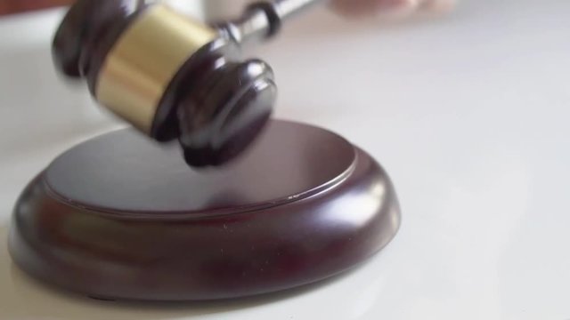 Gavel pounds on block in slow motion.