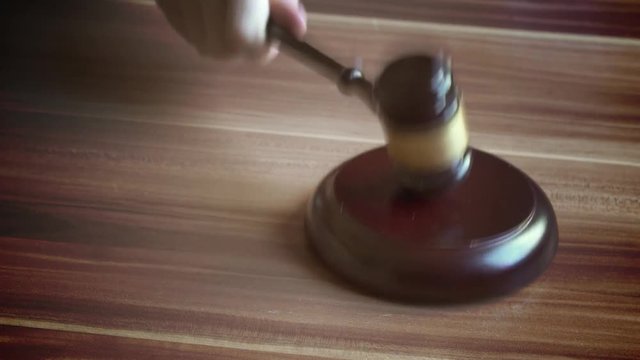 Gavel pounds on block in slow motion.
