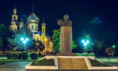 The Church of THE HOLY APOSTLES AND THE GOSPEL JOHN OF BOGHOSLOV and the monument of Taras Shevchenko in the park at autumn night. Pokrov town, Ukraine, 2017