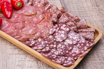 Set of meat delicatessen, tomatoes and peppers on a wooden table.