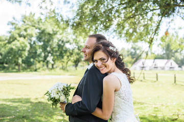 likable and pretty wedding couple stay and hugging in the garden by the tree