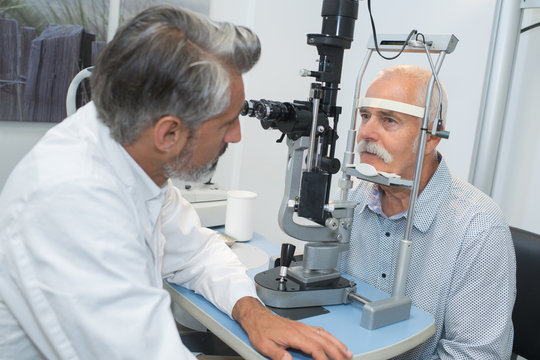 male optician examining senior patients eyes