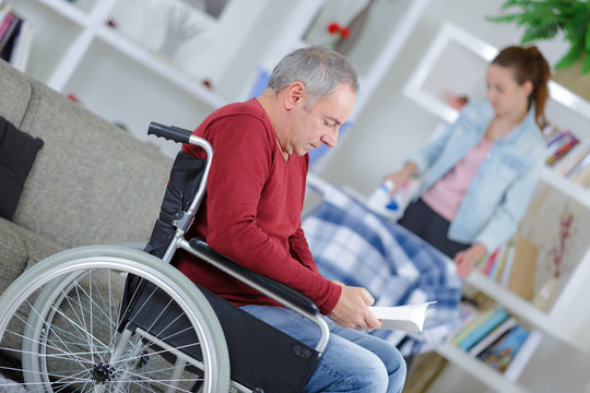 man on wheelchair and nurse helping with ironing