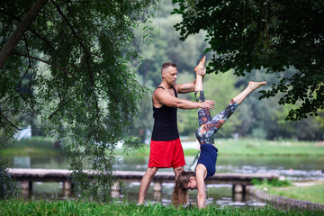 The male instructor helps the girl to do a handstand.