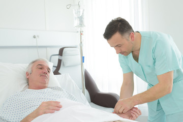 Obraz premium male nurse checking old man patient arterial blood pressure