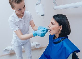 Dentist make x-ray image for young woman in dental clinic. Aiming dental radiography.