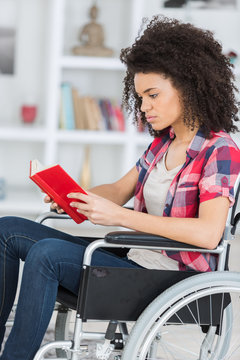 young woman reading book in wheelchair