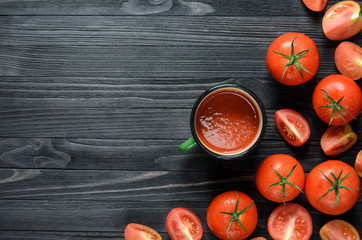 Tomato Juice in Green Enamel Mug on a Black Wooden Table Among Fresh Tomatoes Top View. Background with a Blank Space for Text