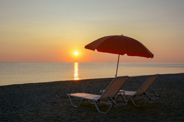 Sunbeds and umbrella on the beach at sunrise