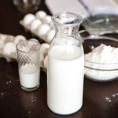 Home cooking still life of eggs in box and milk in glass bottle.