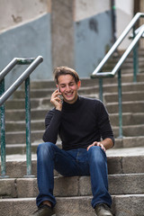 Young man talking on mobile while sitting on outdoor stone steps.