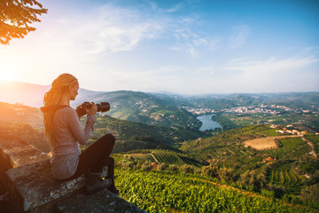 Naklejka na ściany i meble A young woman photographs the Douro Valley, Portugal. Top view of river, and the vineyards are on a hills.