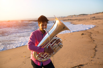 Musician playing the Tuba on the sea coast.