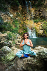 young woman practice yoga outdoor on the rocks by the waterfall