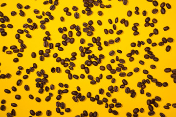 Roasted coffee beans on a yellow background from above
