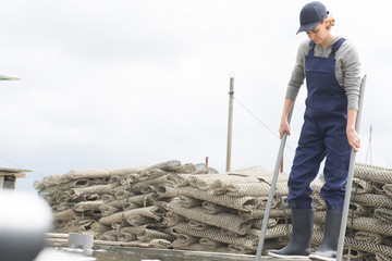 female worker with oysters in metal bag on farm