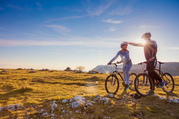Biker couple with mountain bike pointing in distance at countryside © FS-Stock