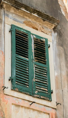 gray brick beige destroyed historic building with rusted closed shutters on a sunny day