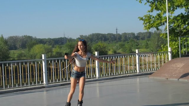 Beautiful girl on roller skates with the camera. The girl shoots herself on GoPro.
