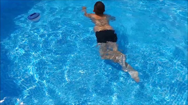Young happy boy swimming in the swimming pool. 