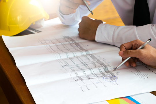 Two business man or engineer talking and discussion with sketched blueprint