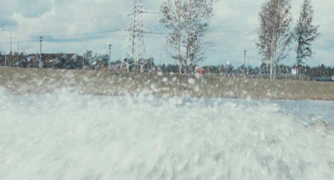 Attractive female practicing wakeboarding tricks in a wakepark near a city. 4K UHD 60 FPS 