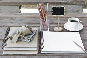 Still life, business, education concept : Close up image open notebook blank pages with glasses, flower bouquet, pencils and coffee cup on wooden table background.