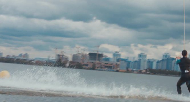 Attractive female wake boarding in a wakepark near a city. 4K UHD 60 FPS 