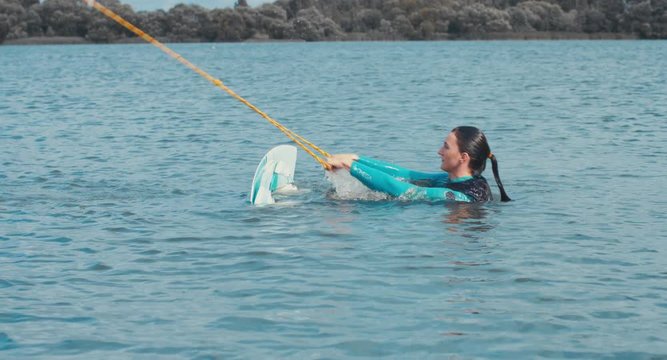 Attractive female wake boarding in a wakepark near a city. 4K UHD 60 FPS 