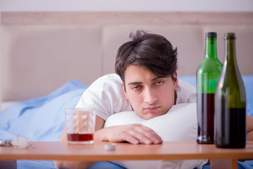 Man alcoholic drinking in bed going through break up depression