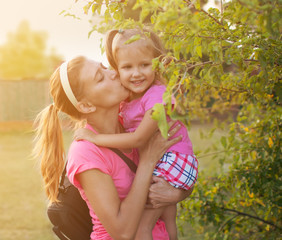 Mom kissing daughter in nature