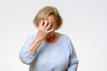 Senior woman covering her face with her hand