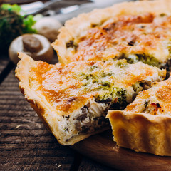Pie with mushrooms, chicken and herbs on the wooden table