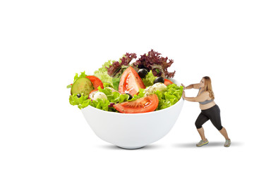 Overweight woman pushing a bowl of salad
