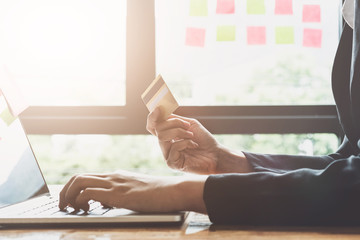 Young woman holding credit card and using laptop computer. Online shopping concept with vintage filter tone