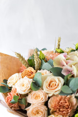Close-up floral composition with roses and mix flowers on a light background.