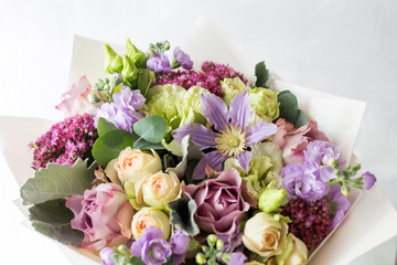 Close-up floral composition with roses and mix flowers on a light background.