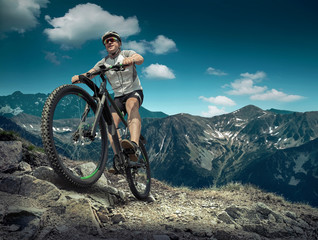 Man in helmet and glasses stay on the bicycle under sky with clo