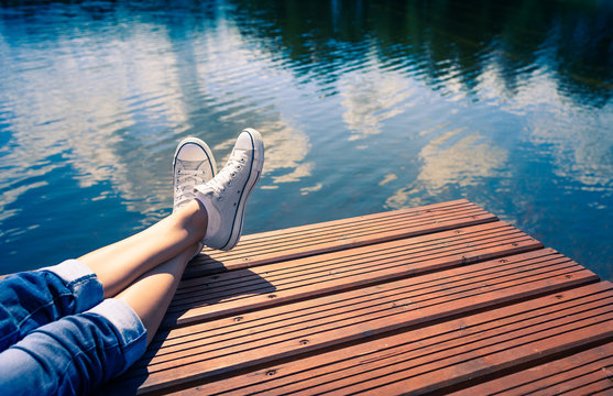 Peaceful  summer holiday. woman on wooden dock relaxing lake side. 