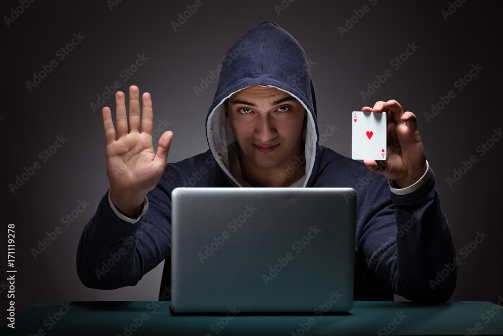 Wall mural Young man wearing a hoodie sitting in front of a laptop computer