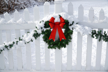 Christmas wreath on the white fence after snow