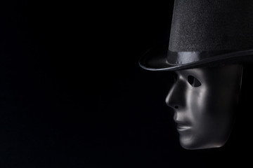 Black mask profile wearing top hat isolated on black background with copy space