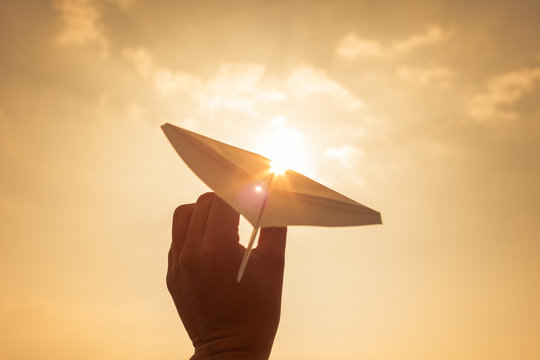 Take off! Hand holding paper airplane in the sky. Dream's, flying, inspiration, freedom concept.  