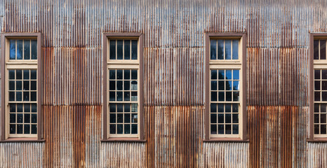 Fototapeta na wymiar Old rusty metal shed with tall windows closeup