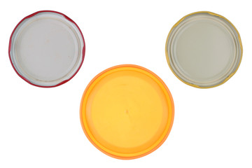 The reverse side of tin and plastic covers from glass jars with canned vegetables.