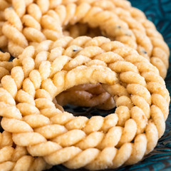 Butter Chakli with spicy famous South Indian Traditional Snack on blue plate. Spiral shaped crisp fried snack. Selective focus. Square image.