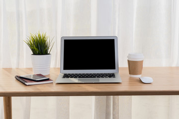 Laptop with smart phone notebook and coffee cup on workplace table.